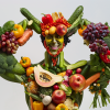 Figura musculosa hecha con frutas y verduras que representa la fuerza y salud de una dieta vegana.