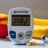 Medidor de glucosa junto a alimentos ricos en carbohidratos para ilustrar el concepto de carga glucémica y su impacto en los niveles de azúcar en sangre