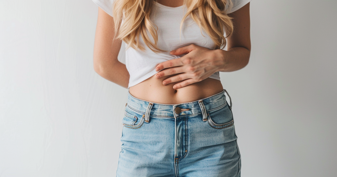 Mujer sujetándose el abdomen por hinchazón abdominal y molestias digestivas.