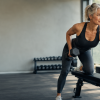 Imagen de una mujer madura entrenando fuerza con mancuerna en un gimnasio, usada como fondo para un post sobre entrenamiento de fuerza en perimenopausia